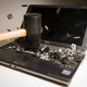 A laptop computer being smashed with a rubber mallet, its keys being flung every direction.